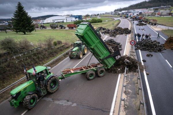 A farmer pulls waste to block the RN 19 near Vesoul, eastern France, on Jan. 25, 2024. French farmers continued their actions on Jan. 25, 2024, and are eagerly awaiting a response from the government to their request for "immediate" aid worth several hundred million euros. (SEBASTIEN BOZON/AFP)