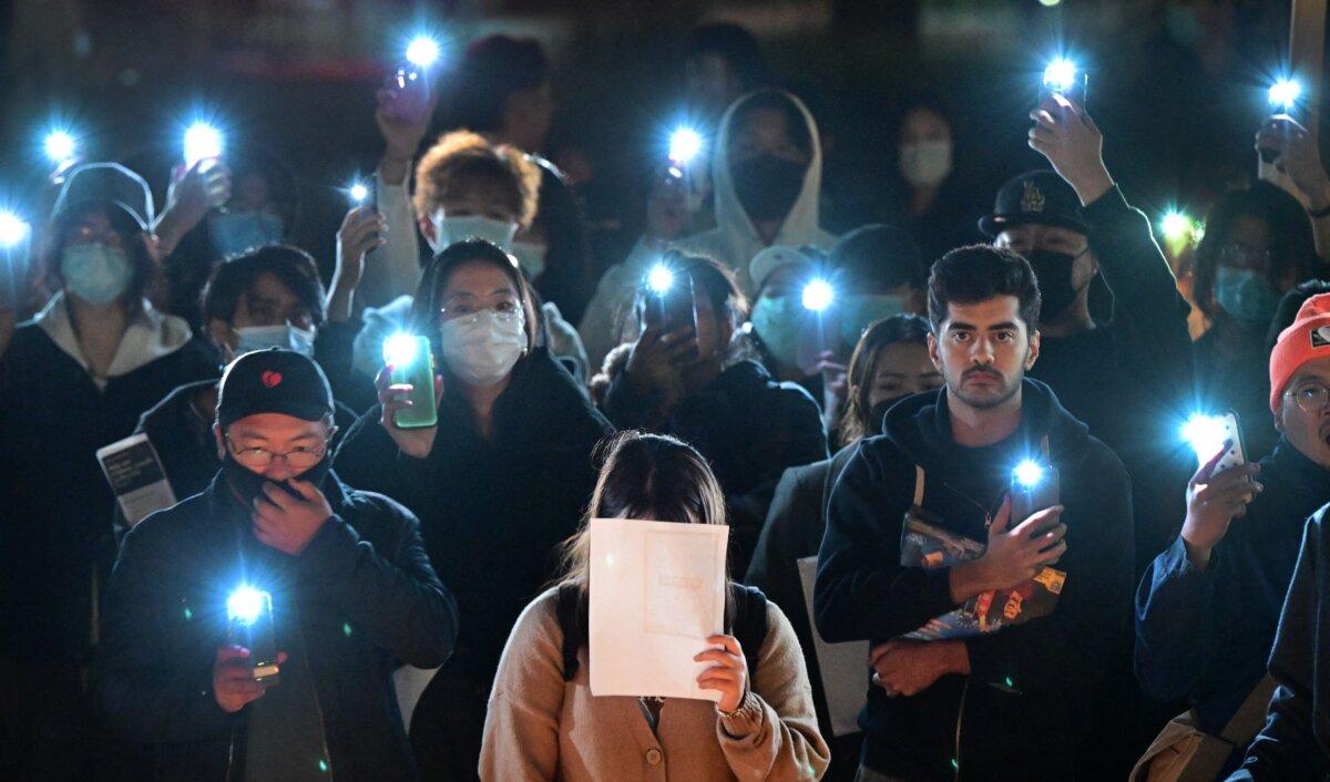 A woman holds a blank sheet of paper as demonstrators protest the deaths caused by an apartment complex fire in Urumqi, Xinjiang, China, at the Langson Library on the campus of the University of California, Irvine, in Irvine, Calif., on Nov. 29, 2022. (Frederic J. Brown/AFP via Getty Images)