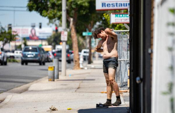 A homeless man begins to contort his body while working off a drug high in Santa Ana, Calif., on June 28, 2022. (John Fredricks/The Epoch Times)