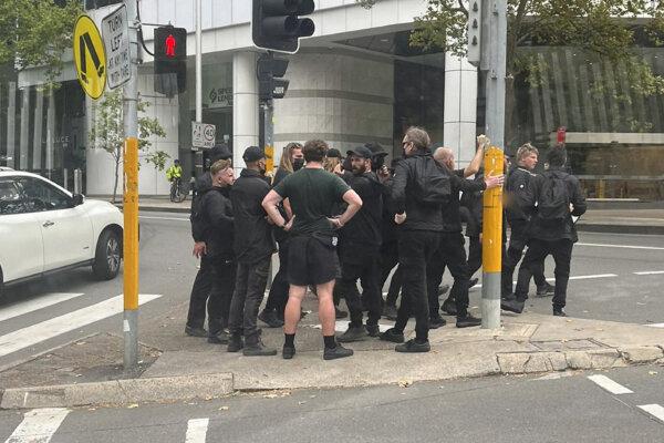 A supplied image shows leader of the National Socialist Network Thomas Sewell with a group of men dressed in black near North Sydney train station in Sydney on Jan. 26, 2024. A group of about 40 men in balaclavas are being held in North Sydney by police after swarming a train and waving Australian flags. (AAP Image/Supplied)