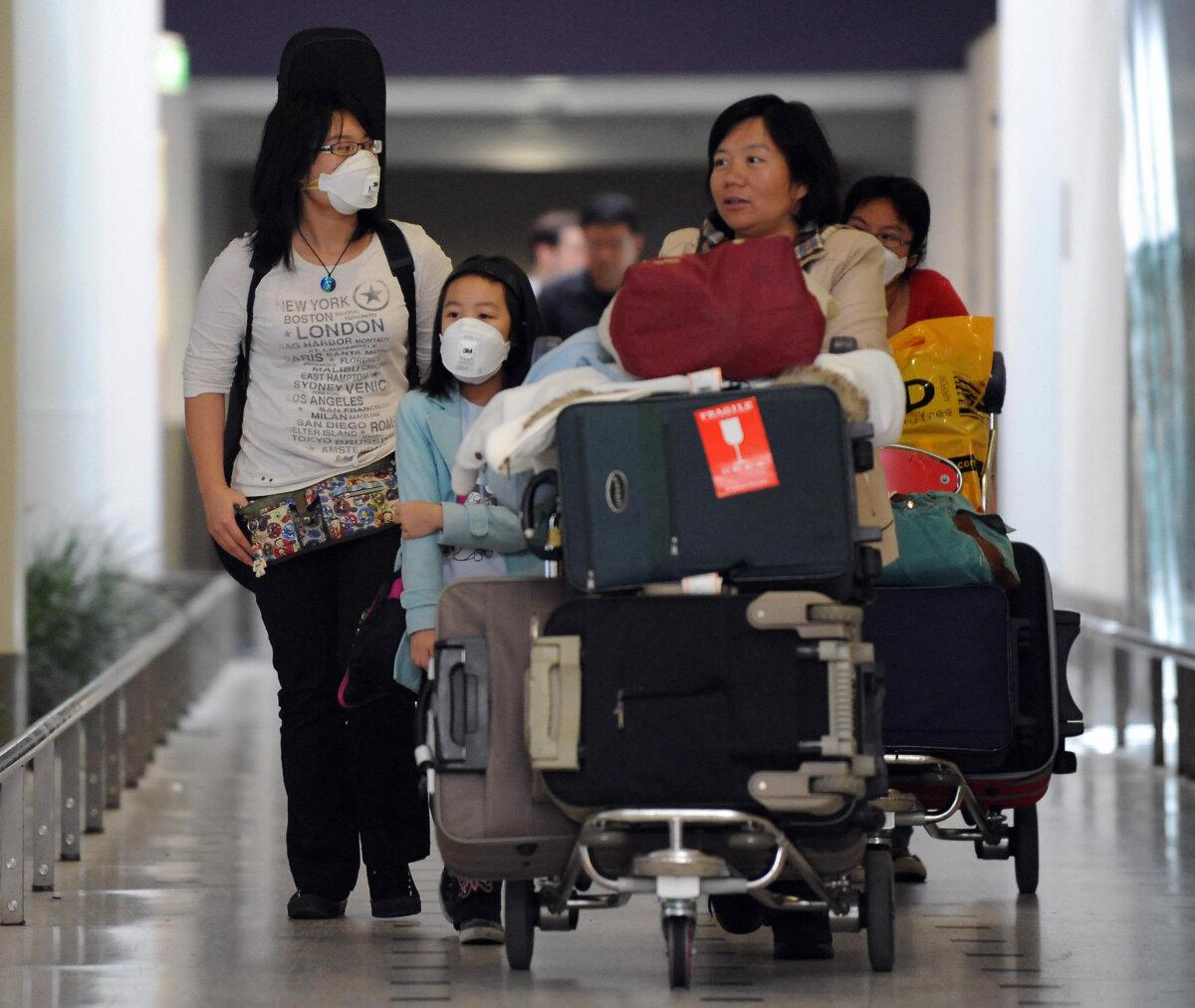 A family from Hong Kong arrives at Sydney International Airport in Australia on April 28, 2009. (Torsten Blackwood/AFP via Getty Images)