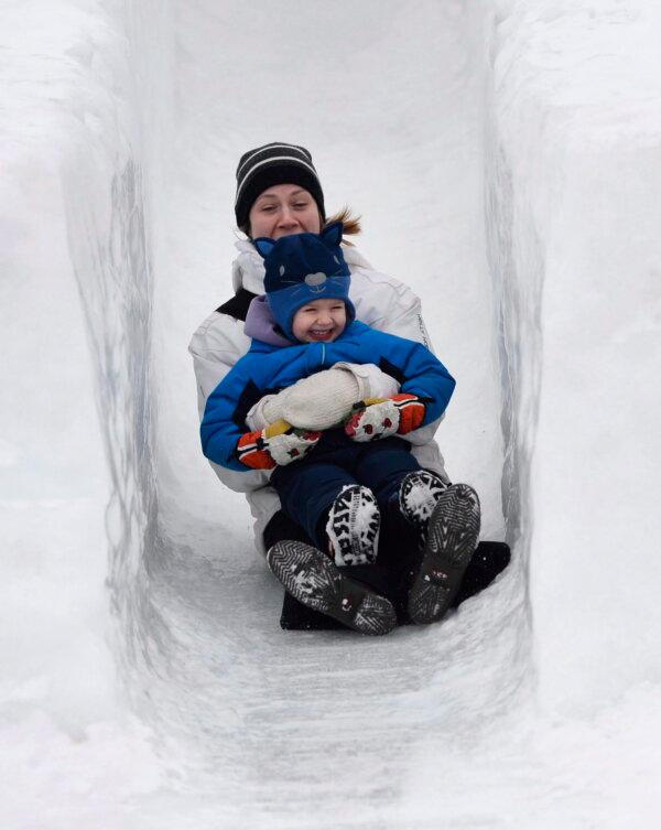 A mother and daughter slide down an ice slide at Jacques-Cartier Park in Gatineau during the Winterlude Festival in 2016. (The Canadian Press/Justin Tang)