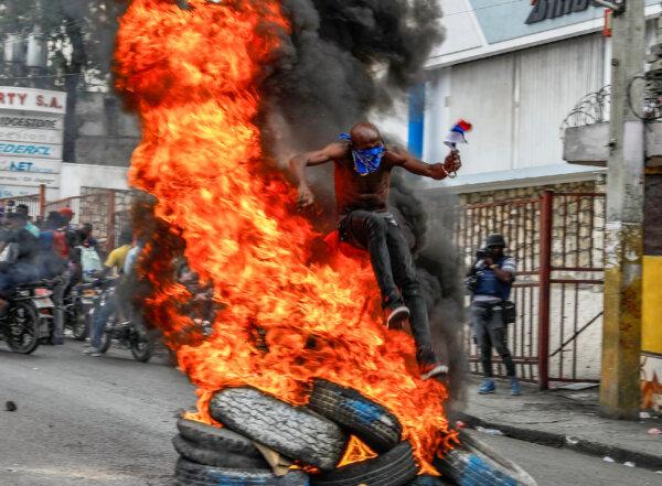 A protester jumps burning tires during a protest against Haitian Prime Minister Ariel Henry in Port-au-Prince, Haiti, on Feb. 5, 2024. (Odelyn Joseph/AP Photo)