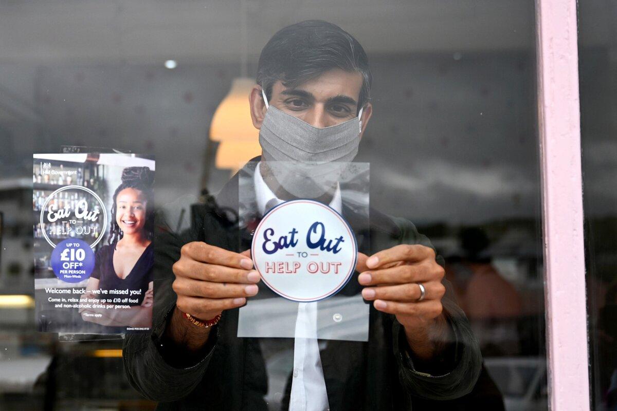 Chancellor of the Exchequer Rishi Sunak places an Eat Out to Help Out sticker in the window of a business, in an undated file photo. (Jeff J Mitchell/PA)