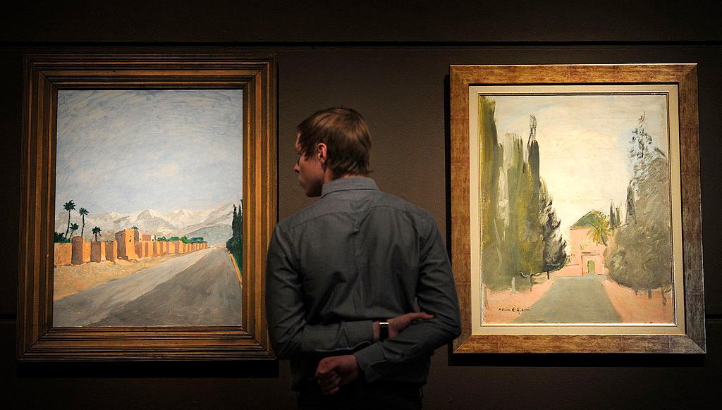 A museum employee looks at a painting by Churchill, “Walls at Marrakech,” (L) at Leighton House Museum in London on Jan. 19, 2012. (CARL COURT/AFP via Getty Images)