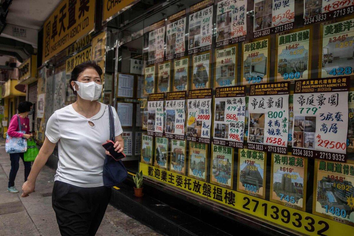 In this picture taken on May 13, 2022, a woman walks past a real estate agent in Hong Kong. (Isaac Lawrence/AFP via Getty Images)