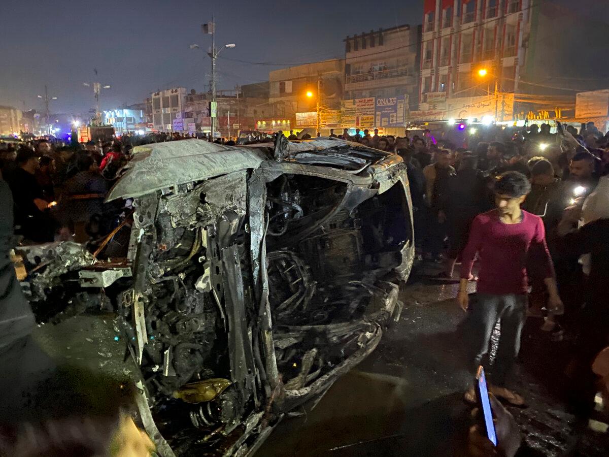 Iraqis gather at the site of a burned vehicle targeted by a U.S. drone strike in Baghdad on Feb. 7, 2024. (Hadi Mizban/AP Photo)