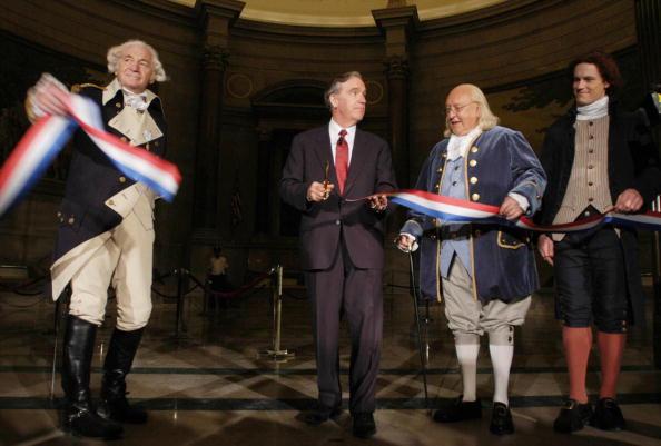 John Carlin (C), archivist of the United States, cuts the ribbon to the National Archives Rotunda which displays the Declaration of Independence, the U.S. Constitution, and the Bill of Rights while (from left) actors portraying our Founding Fathers look on, Sept. 18, 2003. (Nicholas Roberts/ AFP via Getty Images)
