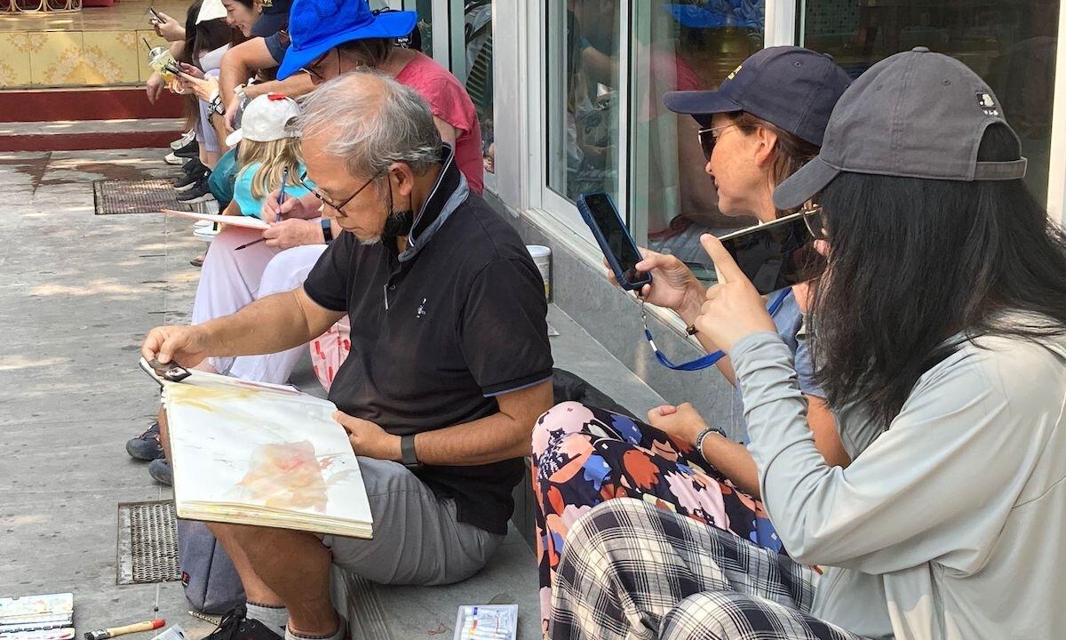 Richie Cheung and friends sketching on the streets of Thailand, attracting passers-by. (Courtesy of Richie Cheung)