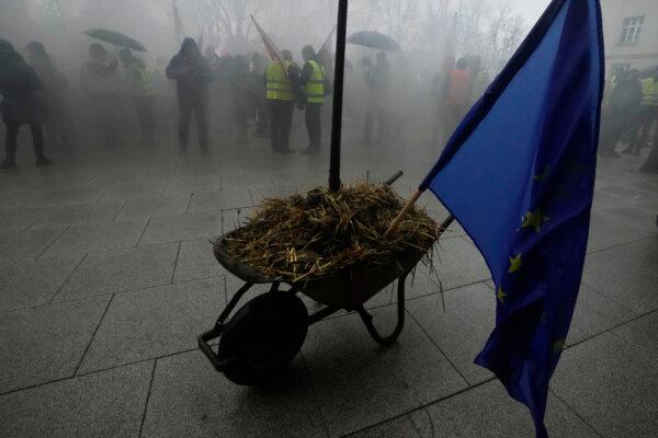 Polish farmers, angry at EU agrarian policy and cheap Ukraine produce imports which, they say, are undercutting their livelihoods, park a wheelbarrow full of manure with the EU flag stuck into it, in a protest in front of the office of the regional governor, in Poznan, western Poland, Friday Feb. 9, 2024. (Czarek Sokolowski /AP Photo)