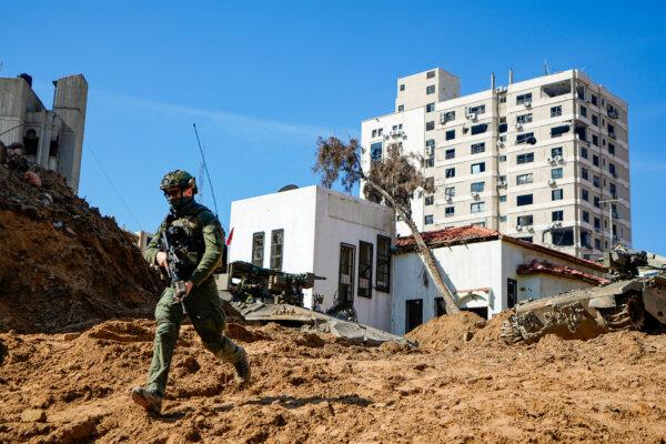 An Israeli soldier runs down a crater-like hole giving way to a tunnel entrance, leading to where the military discovered tunnels underneath the main headquarters of UNRWA, the U.N. agency for Palestinian refugees, in Gaza on Feb. 8, 2024. (Ariel Schalit/AP Photo)