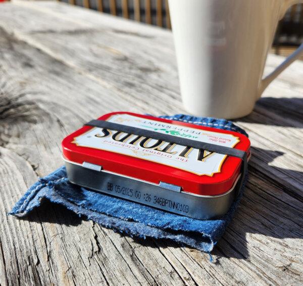 A tactical rubber band secures a makeshift sewing kit kept in a tin mint box as it stands by for use on the patio of a retail business. (Myscha Theriault/TNS)