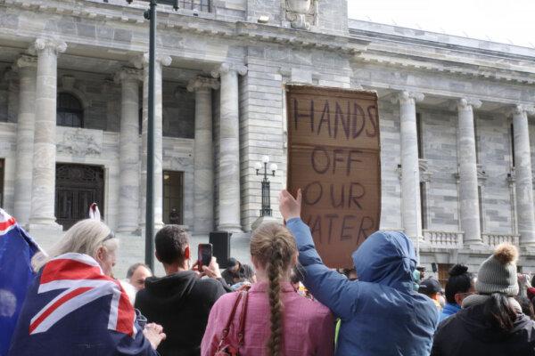Protestors outside Parliament buildings hold up a sign reading "Hands Off Our Water" in protest at the government's planned Three Waters reforms in Wellington, New Zealand, on Aug. 23, 2022. (Lynn Grieveson/Getty Images)