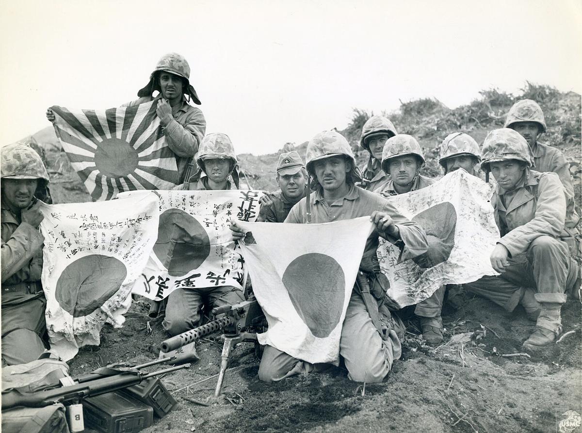 From official USMC photography comes a vista of American soldiers holding up captured Japanese flags, won during the first conflicts on Iwo Jima. (Ser Amantio di Nicolao/<a href="https://creativecommons.org/licenses/by/2.0/deed.en">SA CC-BY 2.0</a>)