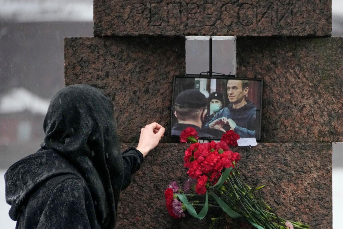 A woman touches a photo of Alexei Navalny after laying flowers paying the last respect to him at the Memorial to Victims of Political Repression in St. Petersburg, Russia, on Feb. 17, 2024. (Dmitri Lovetsky/AP Photo)