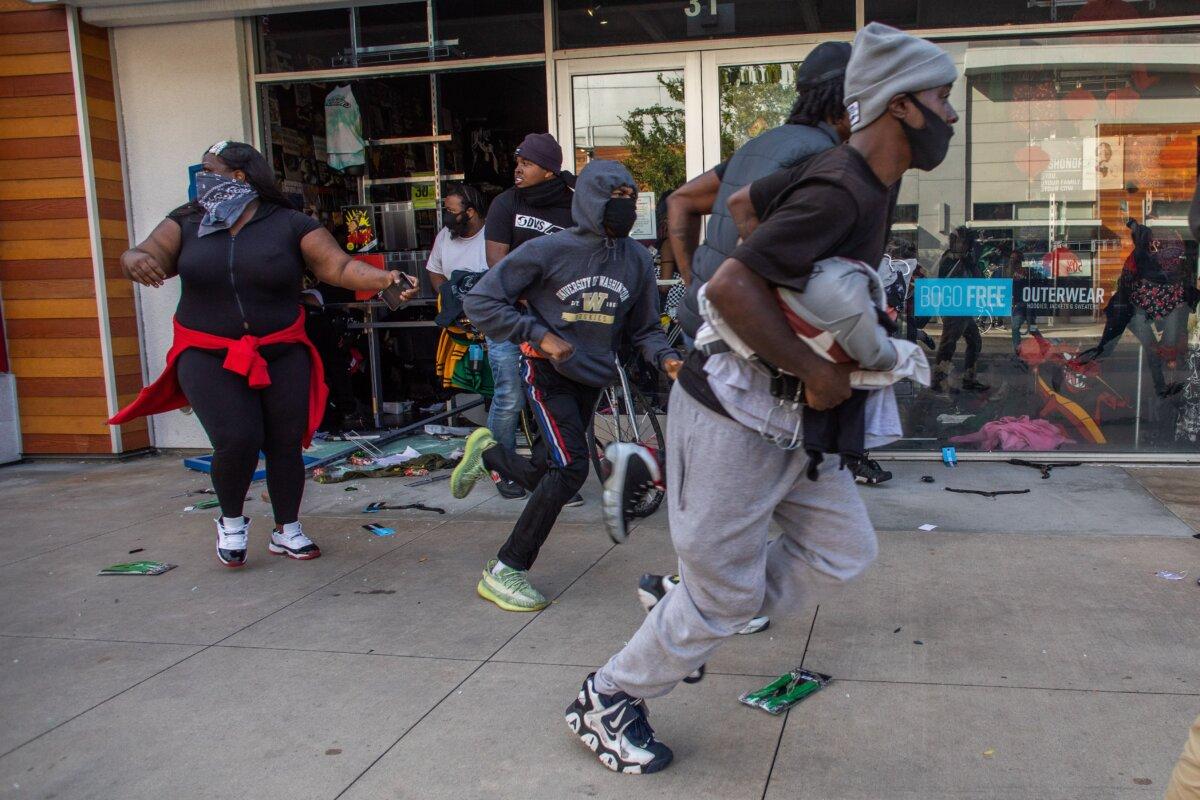 People run with items looted in a clothing store in downtown Long Beach, Calif., on May 31, 2020, during a protest against the death of George Floyd in Minneapolis. (Apu Gomes/AFP via Getty Images)