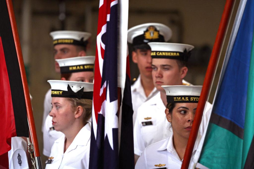 Sailors from the Royal Australian Navy stand behind flags aboard the Australian Navy ship HMAS Canberra in Sydney, Australia, on Feb. 20, 2024. (David Gray/AFP via Getty Images)
