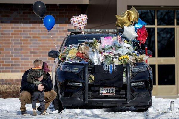 Zach Osterberg, of the Savage Fire Department, hugs his son Lincoln as they paid their respect at three memorials in front of the Burnsville Police Department in Burnsville, Minn., on Feb. 19, 2024. (Elizabeth Flores/Star Tribune via AP)