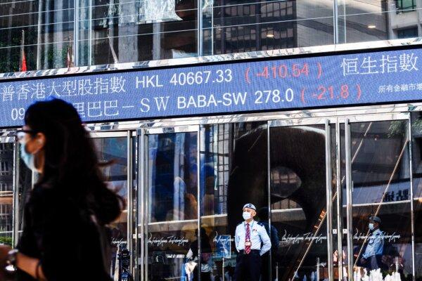 Stock activity of the Alibaba Group Holding Ltd (BABA-SW) (top C) is displayed above a security guard as he stands outside the Exchange Square towers in Hong Kong on Nov. 4, 2020. (Anthony Wallace/AFP via Getty Images)