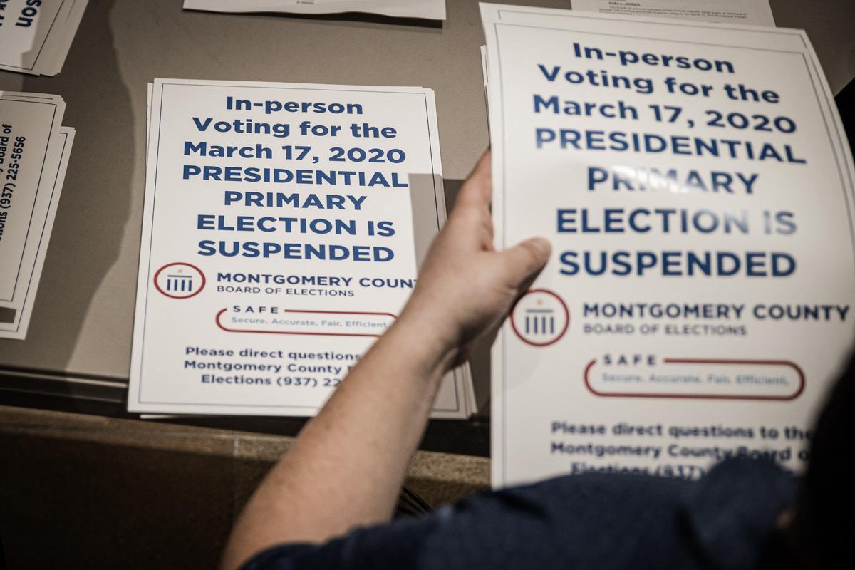 County election workers hand out "election is suspended " signs to put up at polling stations after the primaries were canceled, in Dayton, Ohio, on March 17, 2020. (Megan Jelinger/AFP via Getty Images)