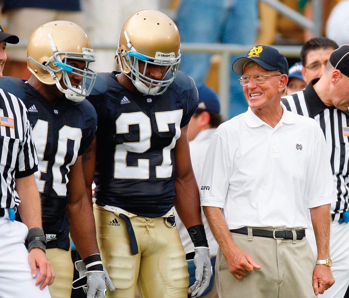 Mr. Holtz stands with Notre Dame players before a game at Notre Dame Stadium in South Bend, Ind., in September 2008. He has led the Fighting Irish to the 1988 National Championship and 100 wins. (Gregory Shamus/Stringer/Getty Images)