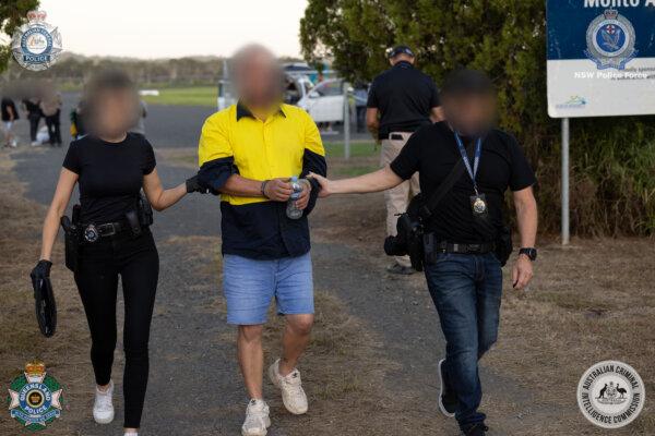 A suspect is led away after a "black flight" was intercepted by law enforcement in Monto, Queensland, Australia, on March 21, 2023. The first five arrests were made in the case after the smuggling flight was intercepted. (Australian Federal Police photo)