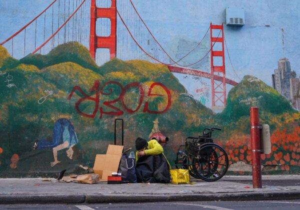 A homeless person lies against a mural of the Golden Gate Bridge in downtown San Francisco on Nov. 11, 2023. (Loren Elliott/AFP via Getty Images)