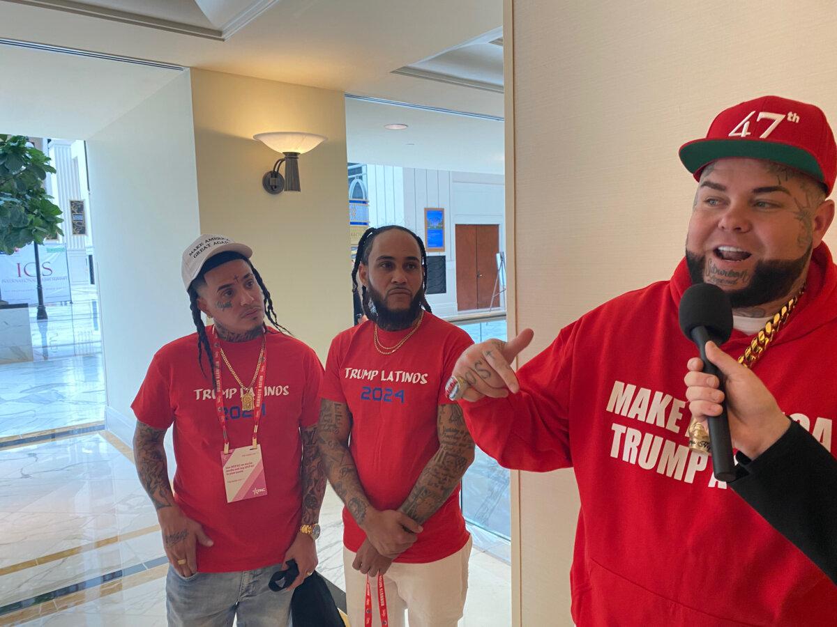 Latino CPAC attendees wearing gear to show their support for former President Donald Trump speak to the press at National Harbor, Md. on Feb. 23. (Joseph Lord/The Epoch Times)