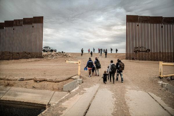 Illegal immigrants from Haiti walk from Mexico through a gap in the border wall into the United States in Yuma, Ariz., on Dec. 10, 2021. (John Moore/Getty Images)