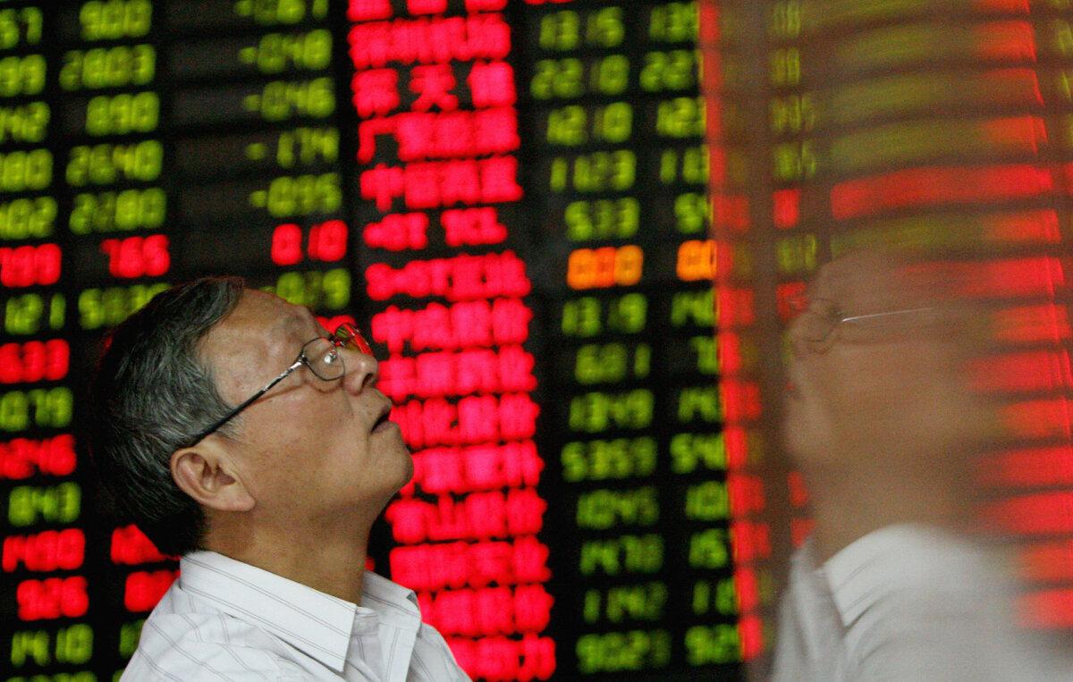 An investor is seen next to a stock price board showing falling prices at a private securities firm in Shanghai, on Oct. 22, 2007. (Mark Ralston/AFP via Getty Images)