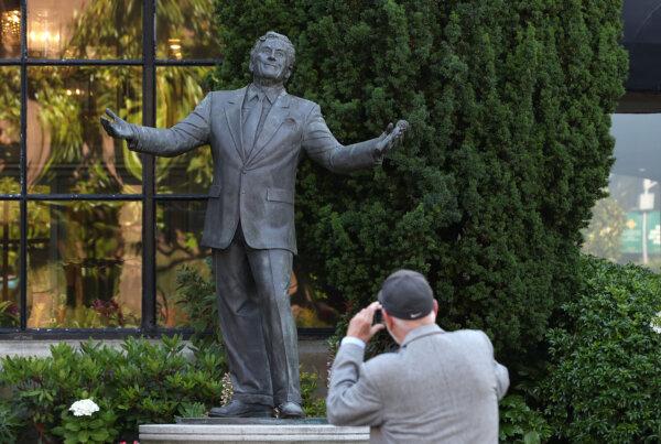 A pedestrian stops to take a picture of a Tony Bennett statue at the Fairmont Hotel on July 21, 2023, in San Francisco. (Justin Sullivan/Getty Images/TNS)