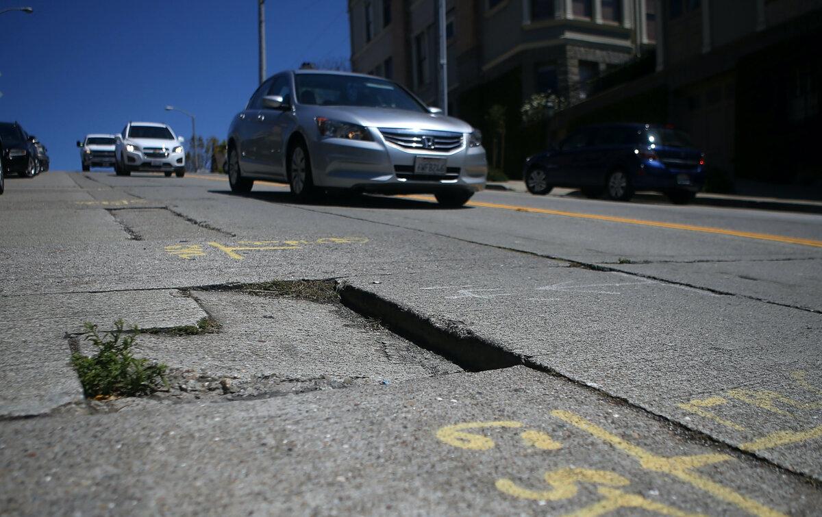 Cars drive by a pothole in a file image taken in San Francisco on July 28, 2015. (Justin Sullivan/Getty Images)