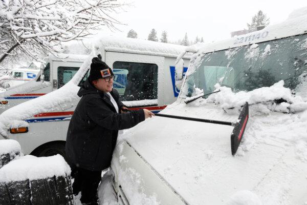 Mail carrier Kirsten Toner scraps the snow of her delivery truck as he preps to make her deliveries in Truckee, Calif., on March 1, 2024. (Andy Barron/AP Photo)