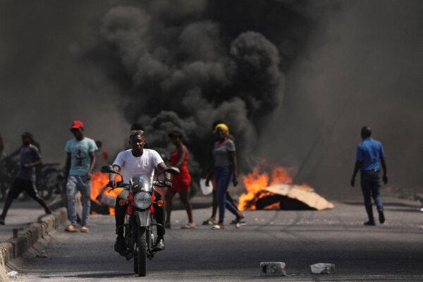A man drives past a burning barricade during a protest against Prime Minister Ariel Henry's government and insecurity, in Port-au-Prince, Haiti, on March 1, 2024. (Ralph Tedy Erol/Reuters)