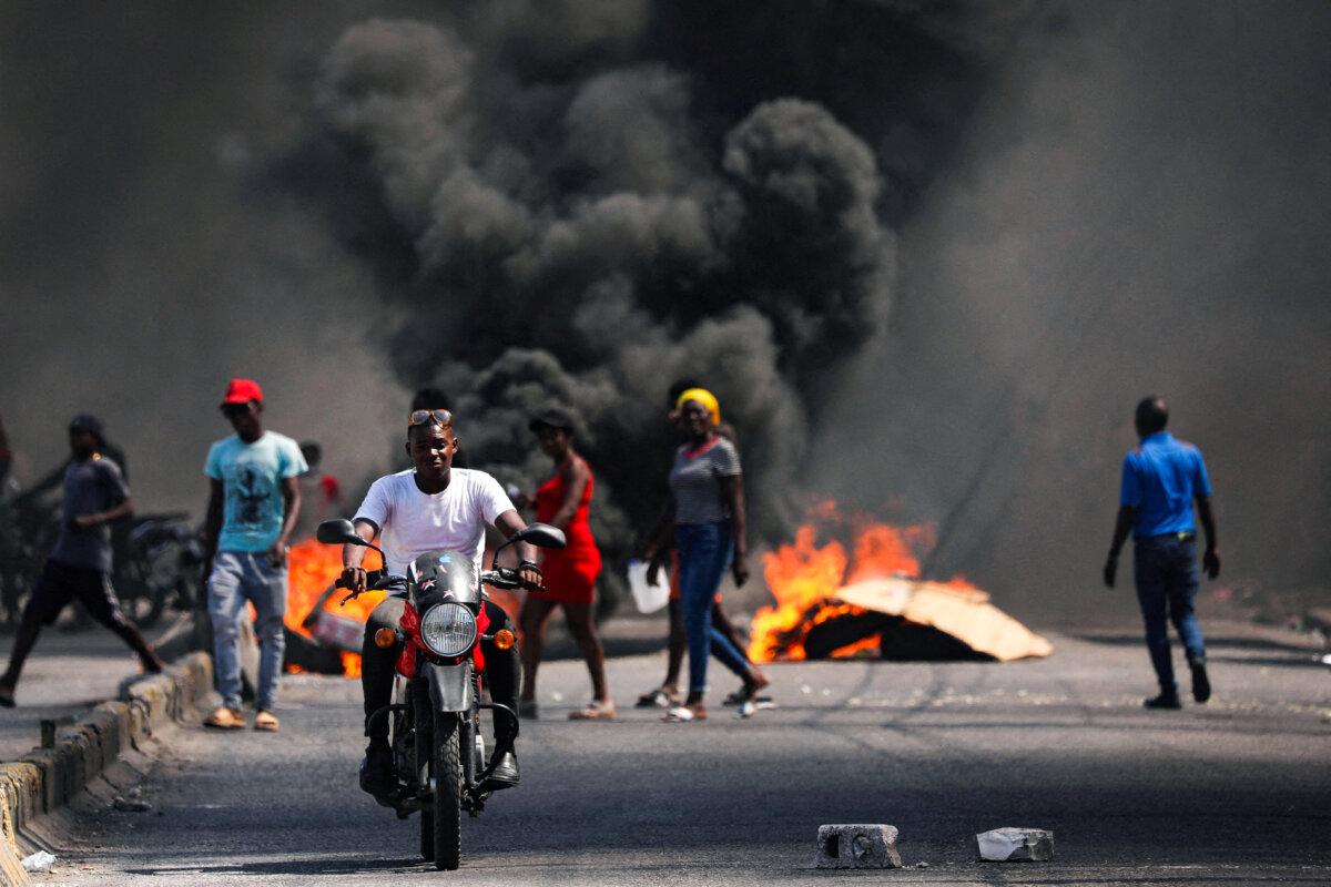 A man drives past a burning barricade during a protest against Prime Minister Ariel Henry's government and insecurity, in Port-au-Prince, Haiti, on March 1, 2024. (Ralph Tedy Erol/Reuters)