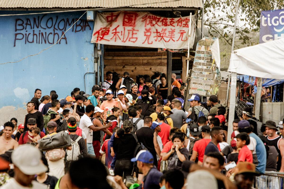 Migrants line up for immigration processing in Lajas Blancas as merchants offer services in both Spanish and Chinese in Panama on Feb. 17, 2024. (Bobby Sanchez for The Epoch Times)
