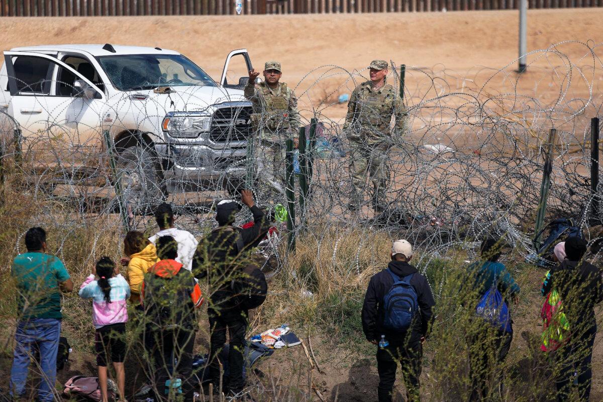 Texas National Guard members prevent illegal immigrants from Venezuela from crossing a barbed wire fence at the El Paso Sector Border after they had crossed the Rio Grande from Ciudad Juarez, Mexico, on Feb. 29, 2024. (Herika Martinez/AFP via Getty Images)