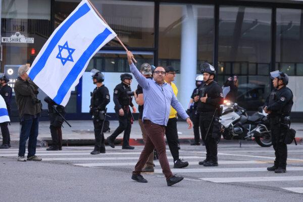 A supporter of Israel waves a flag by police officers as pro-Palestinian protesters rally by the Beverly Center shopping center in Los Angeles on Dec. 23, 2023. (David Swanson/AFP via Getty Images)