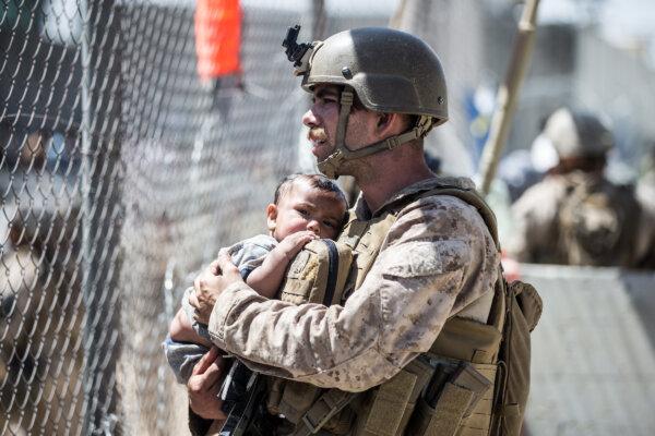A Marine with Special Purpose Marine Air-Ground Task Force-Crisis Response-Central Command (SPMAGTF-CR-CC) calms a child during an evacuation at Hamid Karzai International Airport, Kabul, Afghanistan, on Aug. 26, 2021. (U.S. Marine Corps photo by Sgt. Samuel Ruiz).