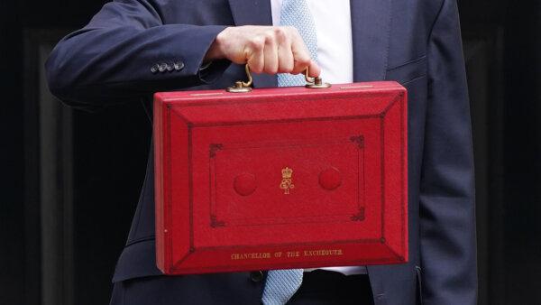 Chancellor of the Exchequer Jeremy Hunt holds up his famous red suitcase as he leaves 11 Downing Street in London on March 6, 2024. (James Manning/PA Wire)