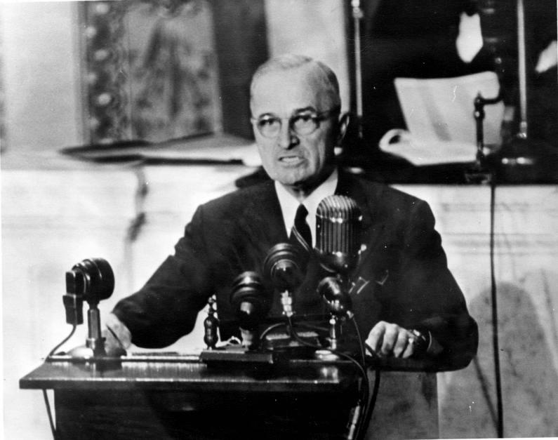 President Harry Truman sits at a desk while delivering a message to Congress about Greece and Turkey, based on the Truman Doctrine. (Public Domain)
