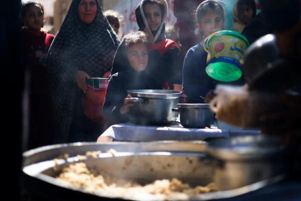Palestinian children wait to receive food cooked by a charity kitchen amid shortages of food supplies, as the ongoing war between Israel and Hamas continues, in Rafah, in the southern Gaza Strip, on March 5, 2024. (Mohammed Salem/Reuters)