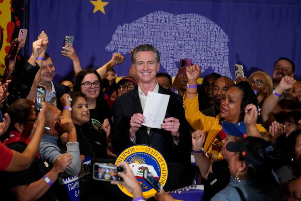 California Gov. Gavin Newsom signs the fast food bill surrounded by fast food workers at the SEIU Local 721 in Los Angeles, on Sept. 28, 2023. (Damian Dovarganes/AP Photo)