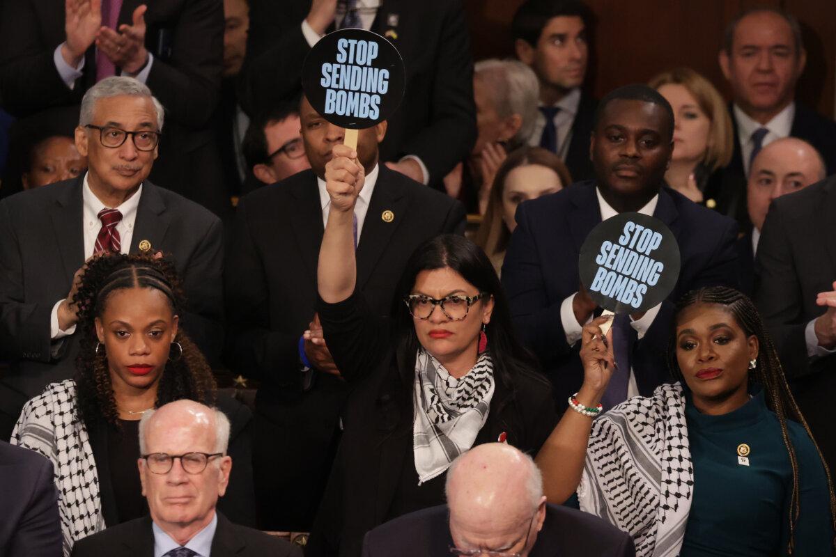 U.S. Rep. Rashida Tlaib (D-MI) (C) and Rep. Cori Bush (D-MO) hold up signs as President Joe Biden delivers the State of the Union address at the Capitol, on March 07, 2024. (Alex Wong/Getty Images)