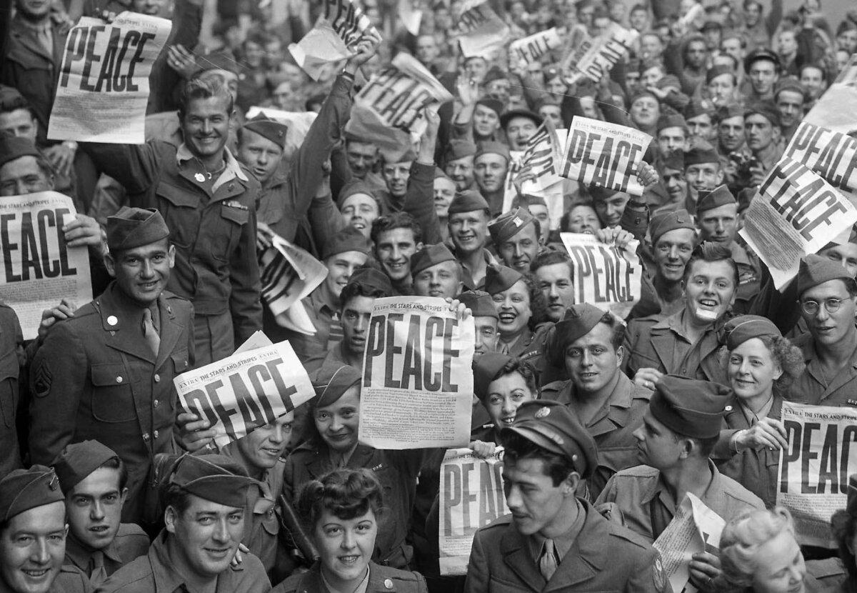 Soldiers hold up the Stars and Stripes newspaper in celebration of the end of WWII in Europe, on May 8, 1945. (First Infantry Division, U.S. Army)