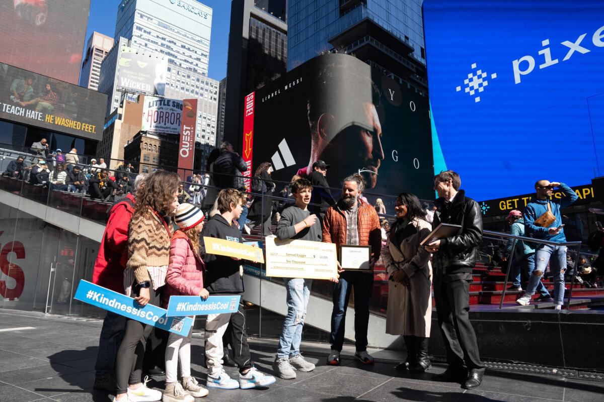 First prize winner Samuel Coggin (C) and his family at Gan Jing World's "Kindness Is Cool Video Awards" ceremony at Times Square, New York, on March 8, 2024. (Larry Dye/The Epoch Times)