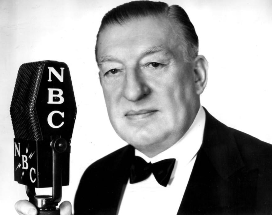 Major Edward Bowes poses for a publicity photo; the microphone indicates that "The Major Bowes Amateur Hour" aired through NBC. (Public Domain)