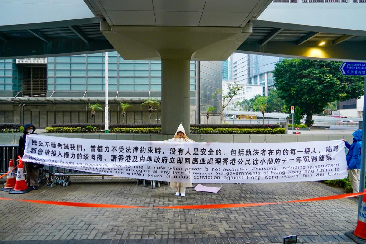 At the request of the police, Ms. Tsui moved to a sidewalk outside the east wing of the Government HQs to continue her petition, where she and two helpers held aloft a banner nearly 5 meters (17 ft.) long. (Kiri Choy/The Epoch Times)