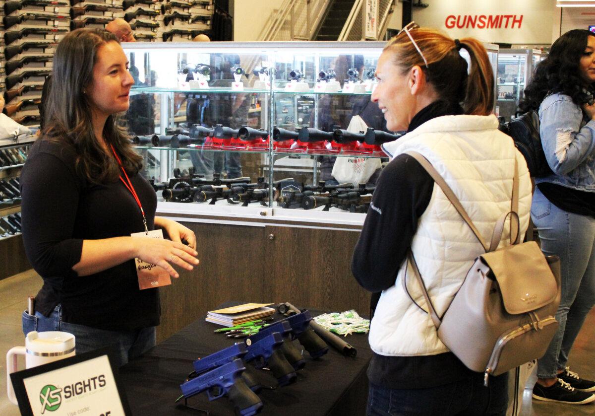 Addison Monroe (L), marketing manager for XS Sights of Fort Worth, Texas, talks with a participant at the National Women's Range Day event at Texas Gun Experience in Grapevine, Texas, on March 9, 2024. (Michael Clements/The Epoch Times)