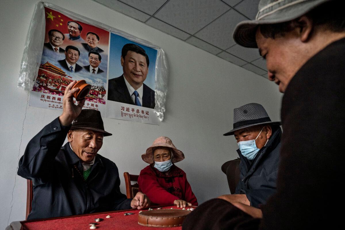 Tibetans play a traditional game under a portrait of President Xi Jinping at a seniors home for elderly people in need in Tibet Autonomous Region on June 18, 2023. (Kevin Frayer/Getty Images)